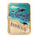 Jervis Bay embroidered travel patch with dolphins leaping offshore and a turtle swimming beside a sandy beach; photographed on a transparent background.