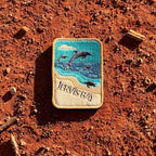 Jervis Bay embroidered travel patch with dolphins leaping offshore and a turtle swimming beside a sandy beach.