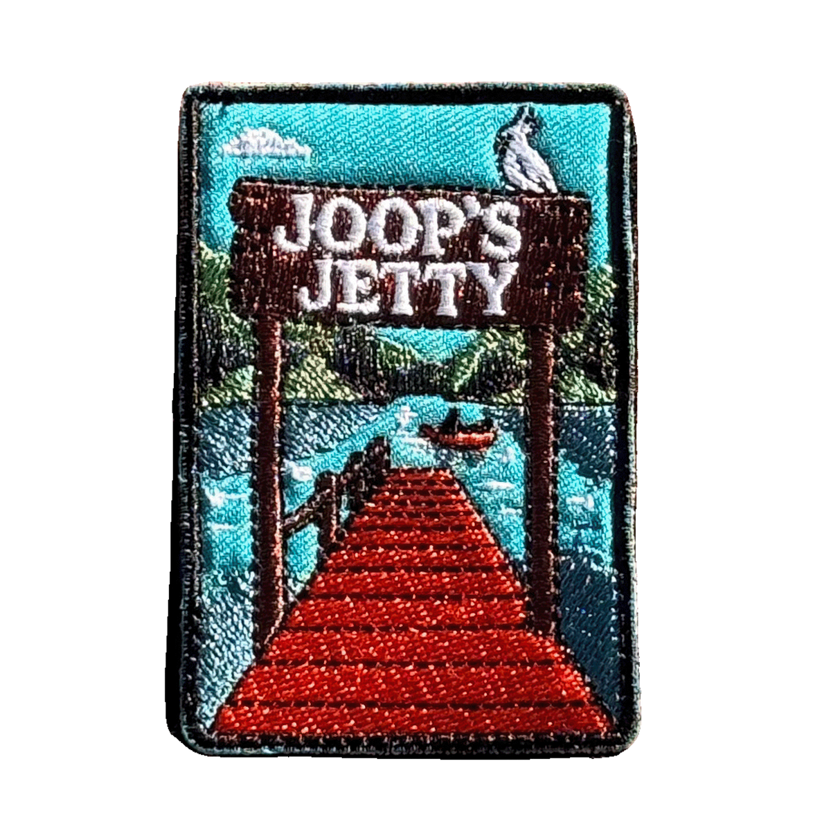 Joop's Jetty - Harrietville embroidered travel patch with a wooden jetty and Joop‚Äôs Jetty sign above a lake with a canoe; photographed on a transparent background.