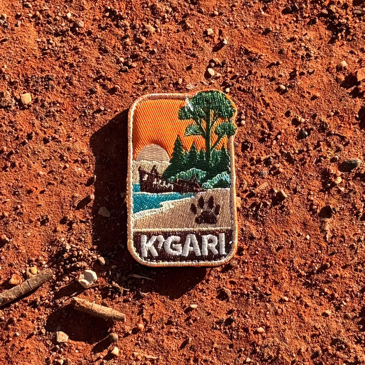 K'gari - Fraser Island embroidered travel patch with a shipwreck on the beach, a dingo paw print and green coastal forest.