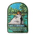 Kakadu - Cahills Crossing embroidered travel patch with a four-wheel drive approaching a river crossing in Kakadu, with trees and a person fishing; photographed on a transparent background.