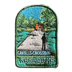 Kakadu - Cahills Crossing embroidered travel patch with a four-wheel drive approaching a river crossing in Kakadu, with trees and a person fishing; photographed on a transparent background.