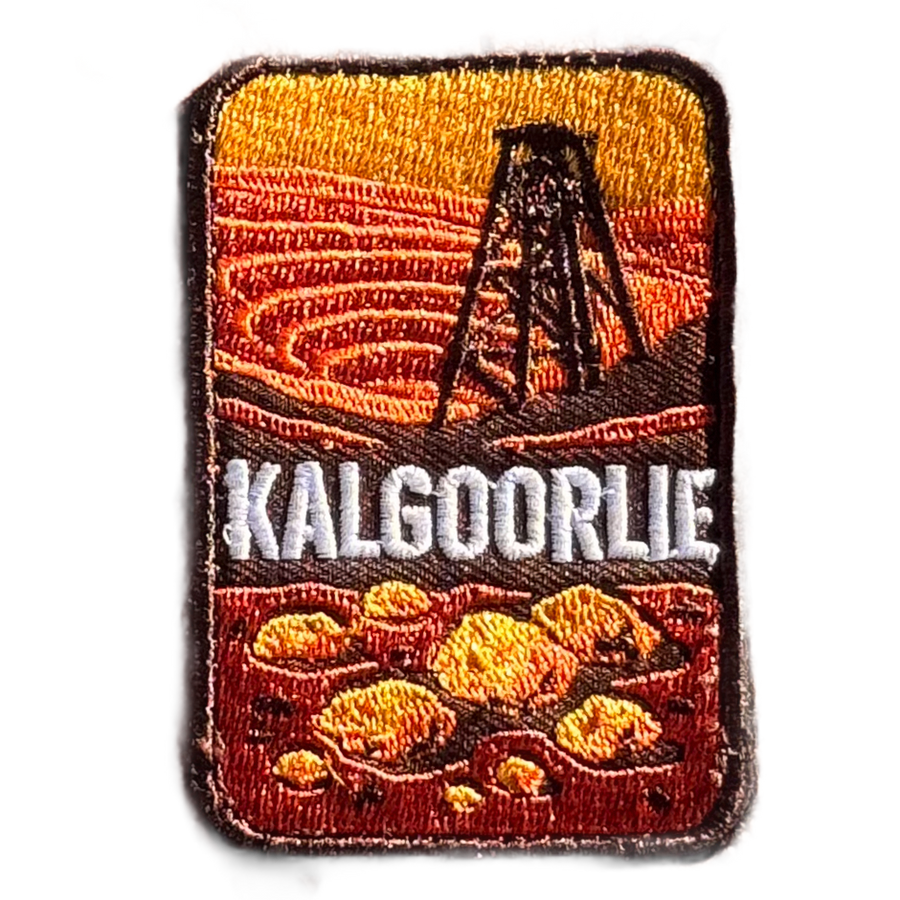 Kalgoorlie embroidered travel patch with a mining headframe above golden nuggets against red outback hills; photographed on a transparent background.