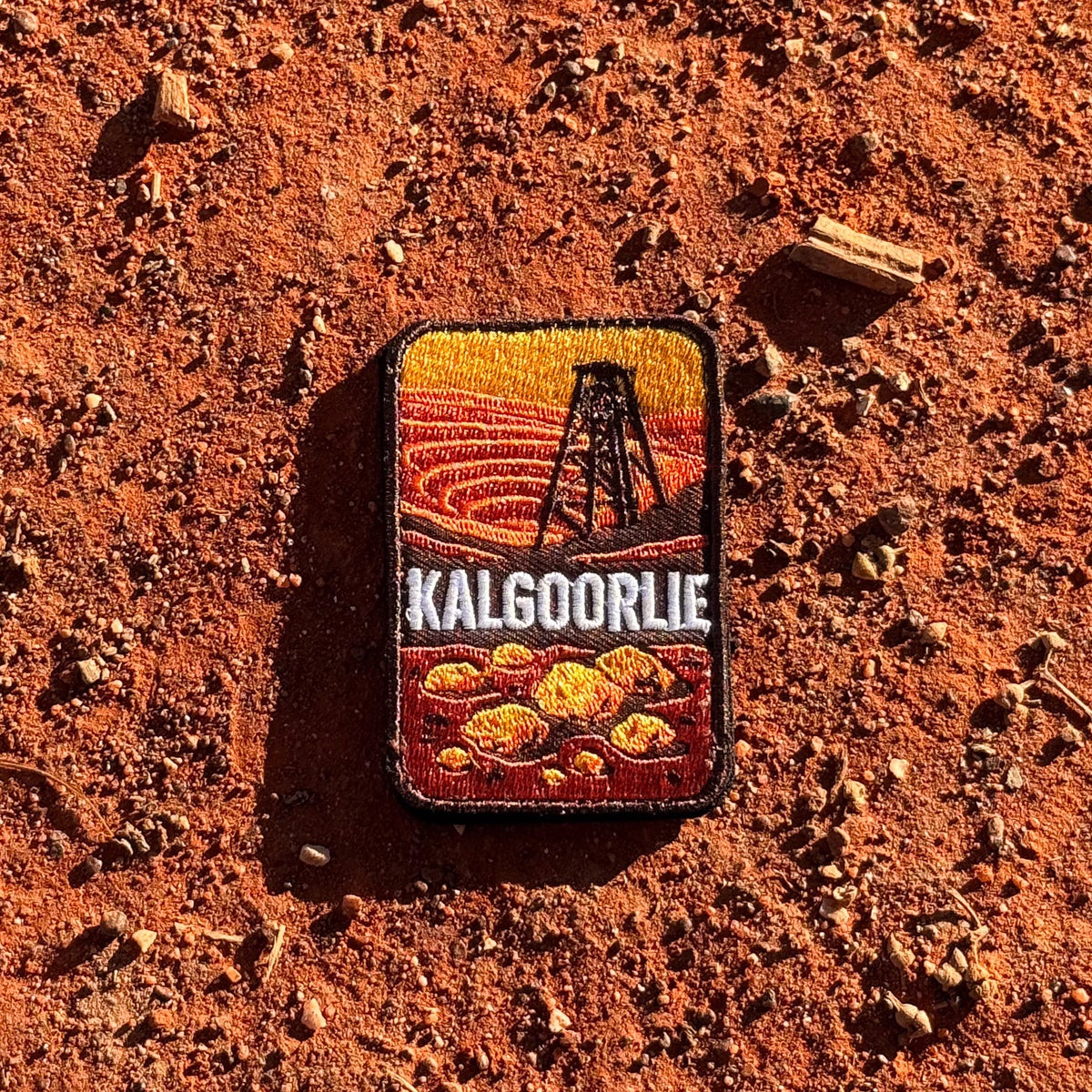 Kalgoorlie embroidered travel patch with a mining headframe above golden nuggets against red outback hills.
