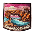 Kangaroo Island embroidered travel patch with a kangaroo on a coastal rock arch and a sea lion beside turquoise water at sunset; photographed on a transparent background.