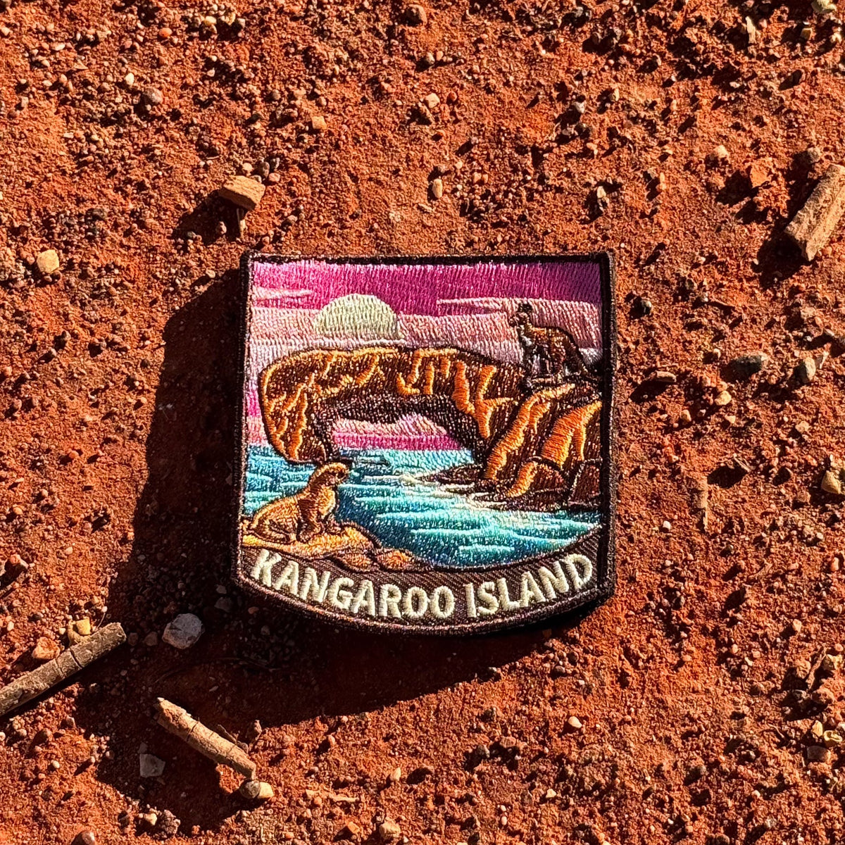 Kangaroo Island embroidered travel patch with a kangaroo on a coastal rock arch and a sea lion beside turquoise water at sunset.
