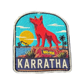Karratha embroidered travel patch with the Red Dog statue on a red rocky hill with an industrial harbour and sunset; photographed on a transparent background.