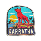 Karratha embroidered travel patch with the Red Dog statue on a red rocky hill with an industrial harbour and sunset; photographed on a transparent background.