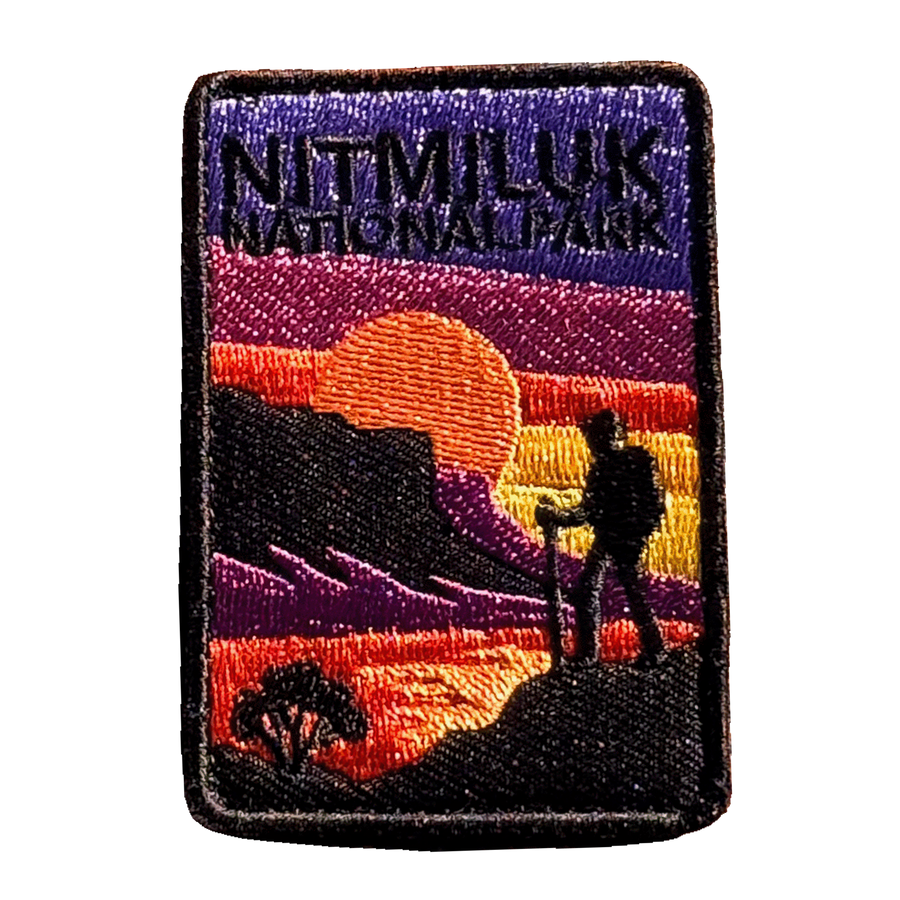 Katherine Gorge (Nitmiluk) embroidered travel patch with a hiker silhouetted against an orange sunset and gorge cliffs at Nitmiluk National Park; photographed on a transparent background.