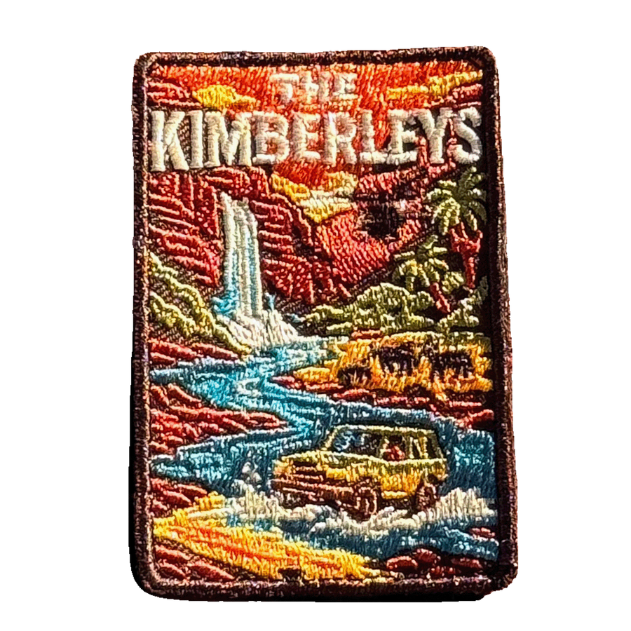 The Kimberleys embroidered travel patch with a waterfall, helicopter, cattle and four-wheel drive in a rugged Kimberley gorge; photographed on a transparent background.