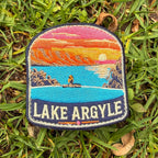 Lake Argyle embroidered travel patch with a swimmer overlooking Lake Argyle and distant mountains at sunset.