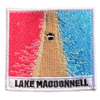 Lake MacDonnell embroidered travel patch with an aerial view of a road separating bright pink and blue lakes; photographed on a transparent background.