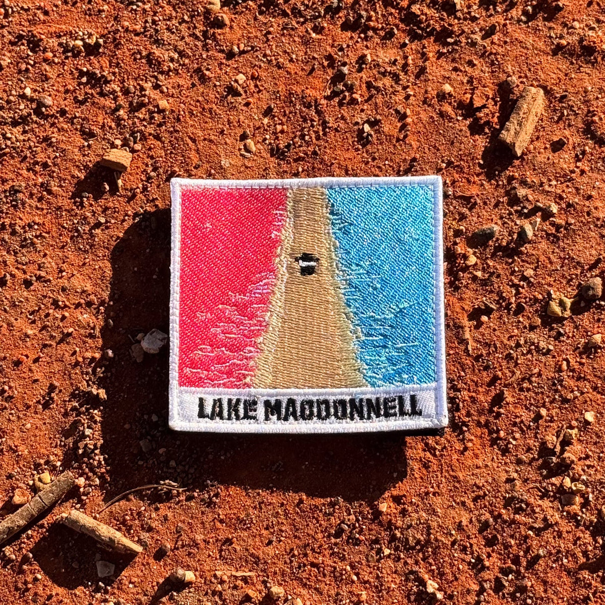 Lake MacDonnell embroidered travel patch with an aerial view of a road separating bright pink and blue lakes.