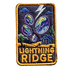 Lightning Ridge embroidered travel patch with colourful opals, lightning and a small mining shack beneath a dark sky; photographed on a transparent background.