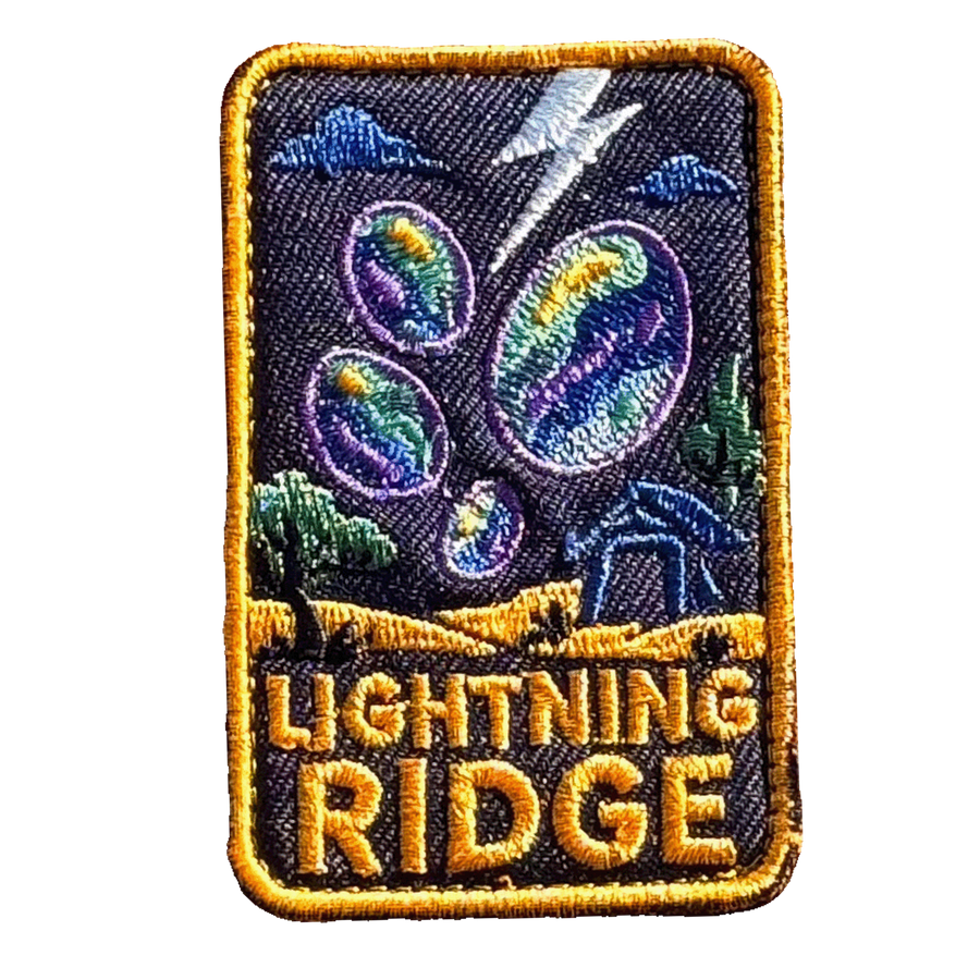 Lightning Ridge embroidered travel patch with colourful opals, lightning and a small mining shack beneath a dark sky; photographed on a transparent background.