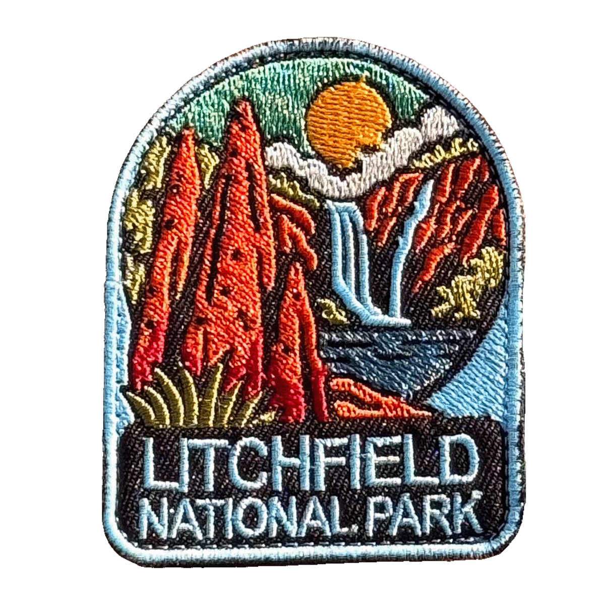 Litchfield National Park embroidered travel patch with red termite mounds, a waterfall and rocky scenery in Litchfield National Park; photographed on a transparent background.