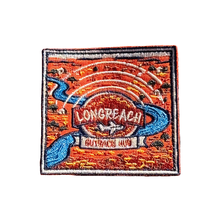 Longreach embroidered travel patch with a map-style outback landscape with a winding river, aircraft and Longreach Outback Hub lettering; photographed on a transparent background.