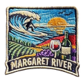 Margaret River embroidered travel patch with a surfer riding a wave above vineyard rows, grapes and a wine glass; photographed on a transparent background.