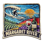 Margaret River embroidered travel patch with a surfer riding a wave above vineyard rows, grapes and a wine glass; photographed on a transparent background.