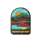 Moreton Bay embroidered travel patch with mangrove trees with exposed roots beside calm coastal water at sunset; photographed on a transparent background.