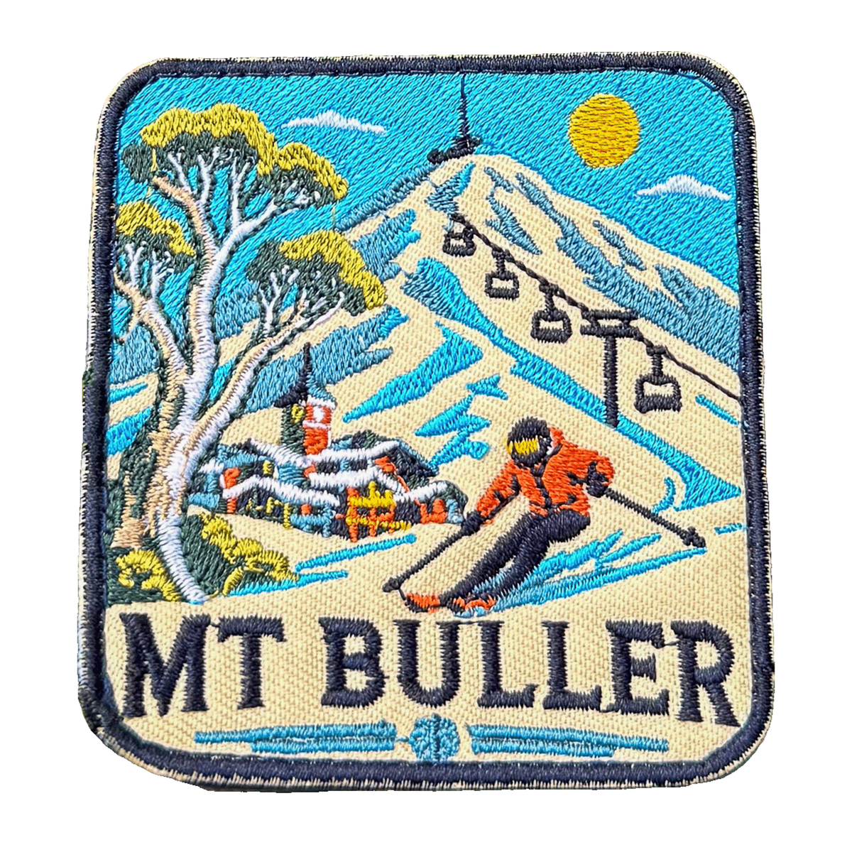 Mount Buller embroidered travel patch with a skier descending a snowy slope beneath chairlifts and a mountain village; photographed on a transparent background.