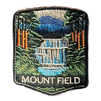 Mount Field National Park embroidered travel patch with a tiered waterfall surrounded by lush green forest; photographed on a transparent background.
