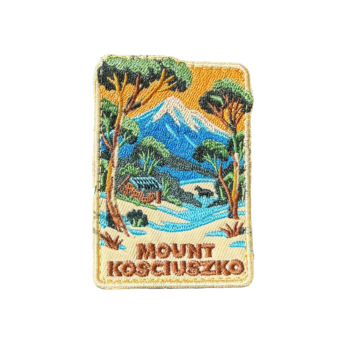 Mount Kosciouzko embroidered travel patch with a snow-covered mountain, alpine cabin, trees and a horse; photographed on a transparent background.