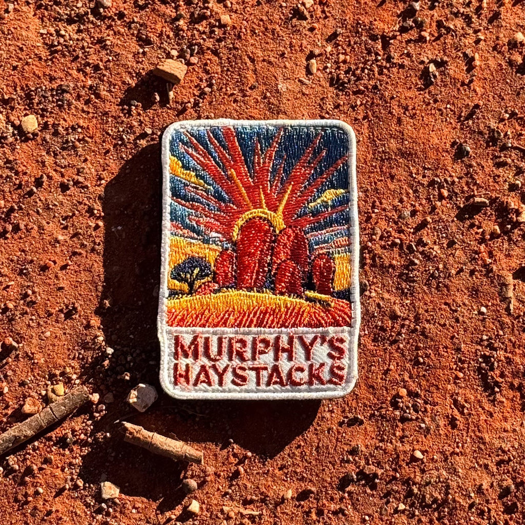 Murphys Haystacks embroidered travel patch with large rounded granite boulders in golden grass beneath a radiant sunset.