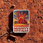 Murphys Haystacks embroidered travel patch with large rounded granite boulders in golden grass beneath a radiant sunset.