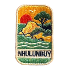 Nhulunbuy - Arnhem Land embroidered travel patch with a rocky tropical shoreline with trees, gentle waves and a setting sun; photographed on a transparent background.