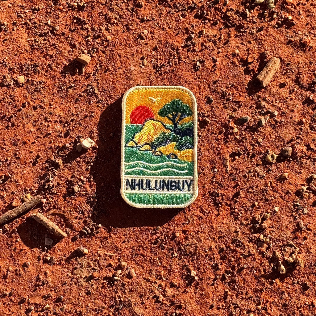 Nhulunbuy - Arnhem Land embroidered travel patch with a rocky tropical shoreline with trees, gentle waves and a setting sun.