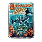Ningaloo Reef embroidered travel patch with a whale shark, manta ray and sea turtle swimming over coral reef; photographed on a transparent background.