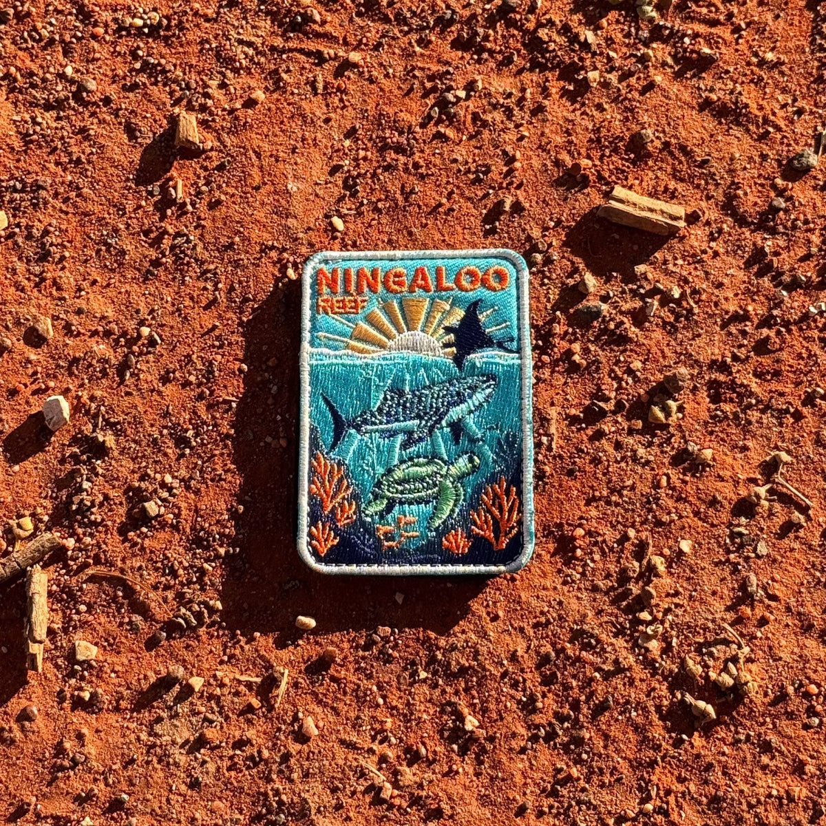Ningaloo Reef embroidered travel patch with a whale shark, manta ray and sea turtle swimming over coral reef.