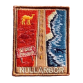 Nullarbor Plain embroidered travel patch with the 90 Mile Straight road between red desert with a camel and coastal cliffs with a whale; photographed on a transparent background.