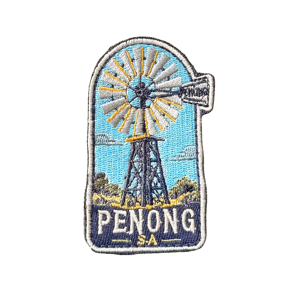 Penong embroidered travel patch with a windmill in a red outback landscape; photographed on a transparent background.