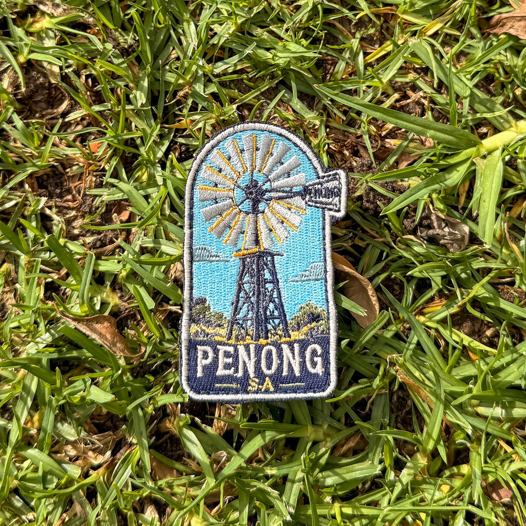 Penong embroidered travel patch with a windmill in a red outback landscape.