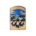Phillip Island embroidered travel patch with three little penguins on a beach with a motorcycle racer and ocean cliffs behind; photographed on a transparent background.