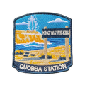 Quobba Blowholes embroidered travel patch with a coastal blowhole spraying above rugged cliffs and ocean; photographed on a transparent background.