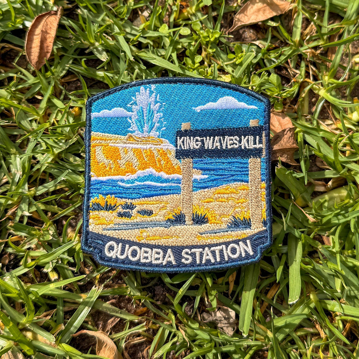 Quobba Blowholes embroidered travel patch with a coastal blowhole spraying above rugged cliffs and ocean.