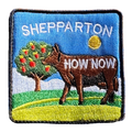 Shepparton embroidered travel patch with a colourful cow sculpture in a regional landscape; photographed on a transparent background.