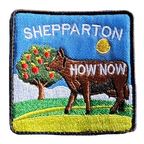 Shepparton embroidered travel patch with a colourful cow sculpture in a regional landscape; photographed on a transparent background.