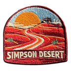 Simpson Desert embroidered travel patch with a four-wheel drive crossing red desert sand dunes; photographed on a transparent background.