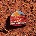 Simpson Desert embroidered travel patch with a four-wheel drive crossing red desert sand dunes.