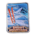 Snowy Mountains embroidered travel patch with snow-covered alpine peaks; photographed on a transparent background.