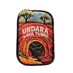 Undara Lava Tubes embroidered travel patch with a lava tube cave opening in an outback landscape; photographed on a transparent background.