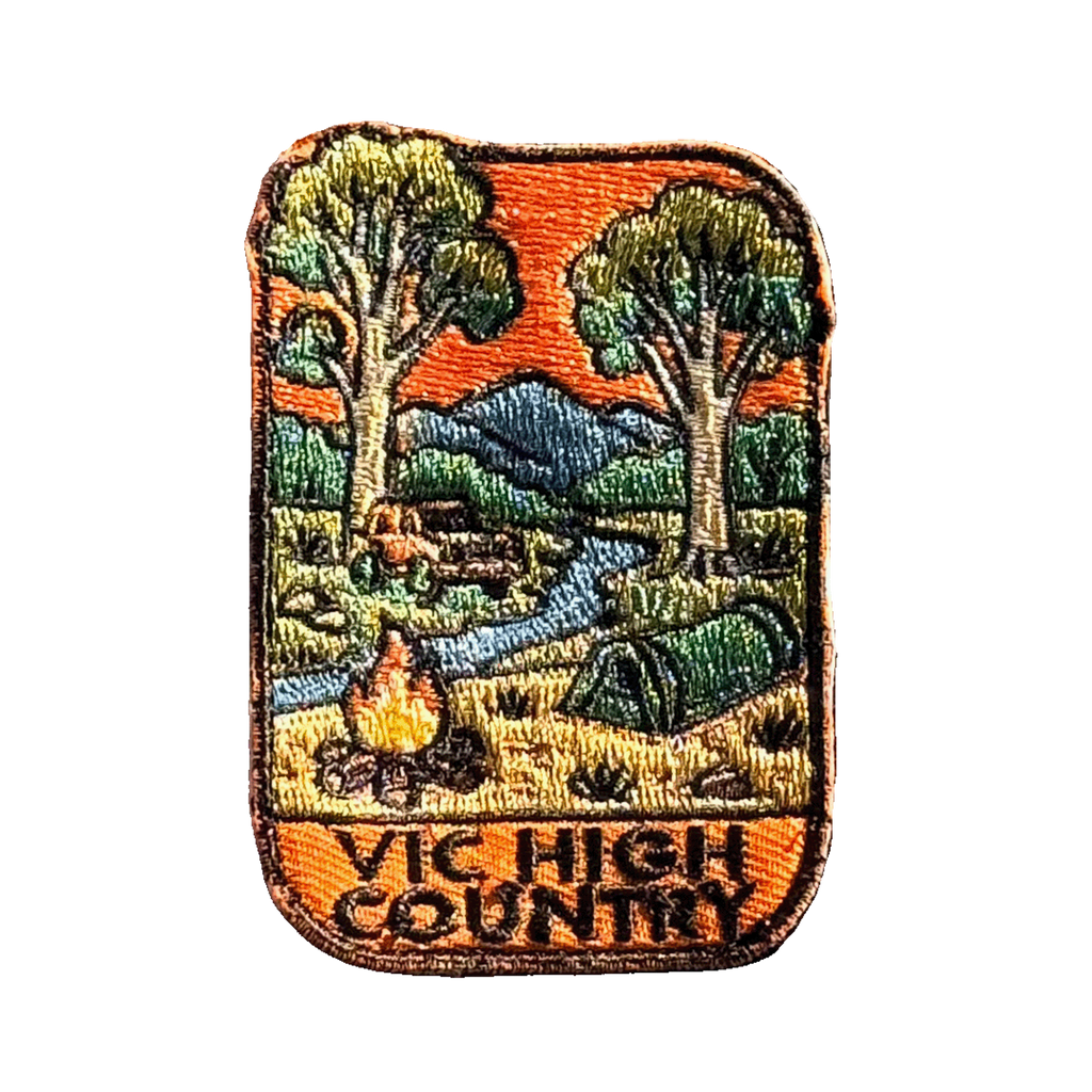 Victorian High Country embroidered travel patch with a four-wheel drive climbing a steep alpine dirt track; photographed on a transparent background.