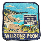Wilsons Promontory embroidered travel patch with a wombat beside the southernmost point of mainland Australia sign and coastal bay; photographed on a transparent background.