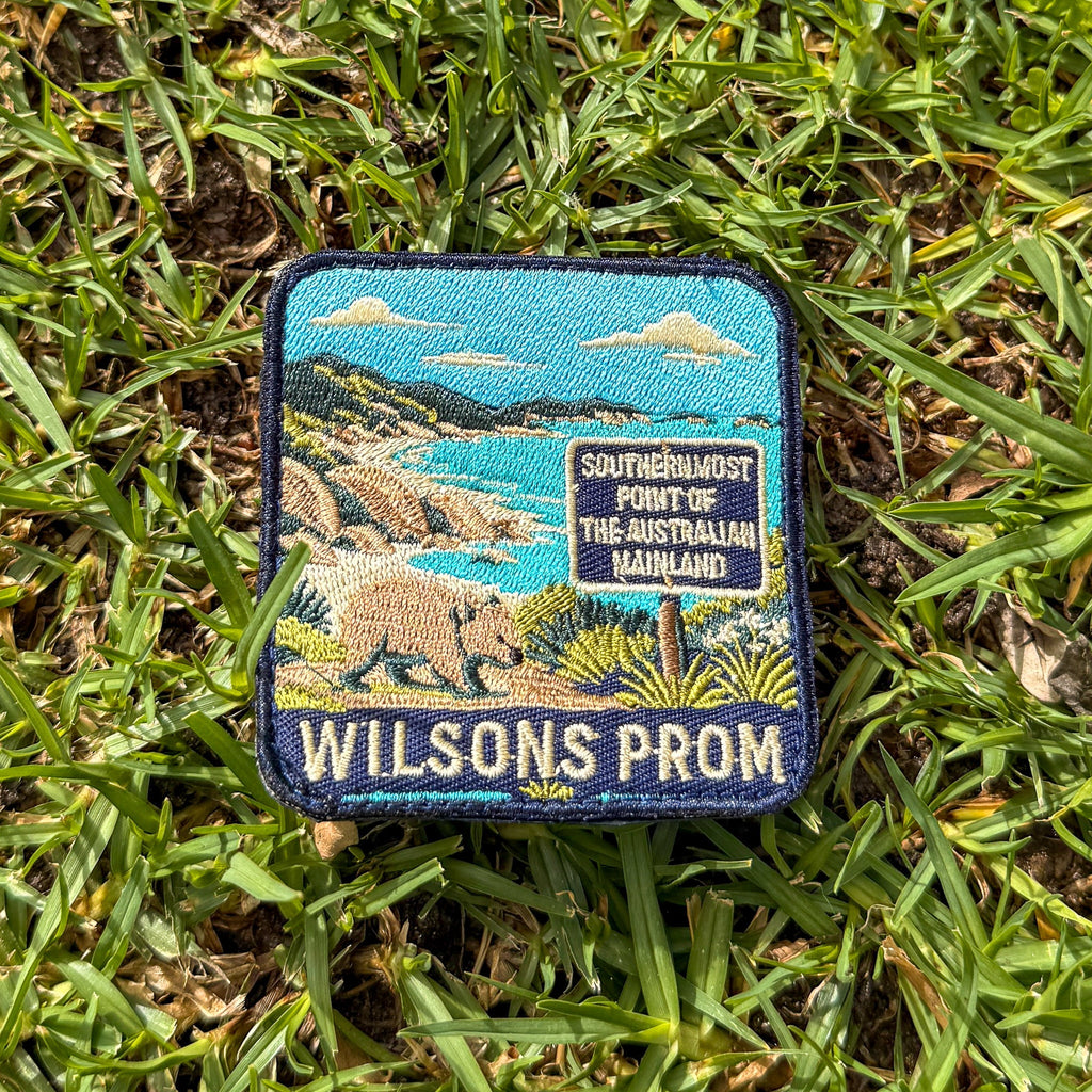 Wilsons Promontory embroidered travel patch with a wombat beside the southernmost point of mainland Australia sign and coastal bay.