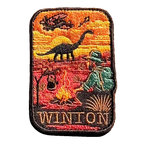 Winton embroidered travel patch with a dinosaur, vintage aircraft and traveller sitting beside a campfire at sunset; photographed on a transparent background.