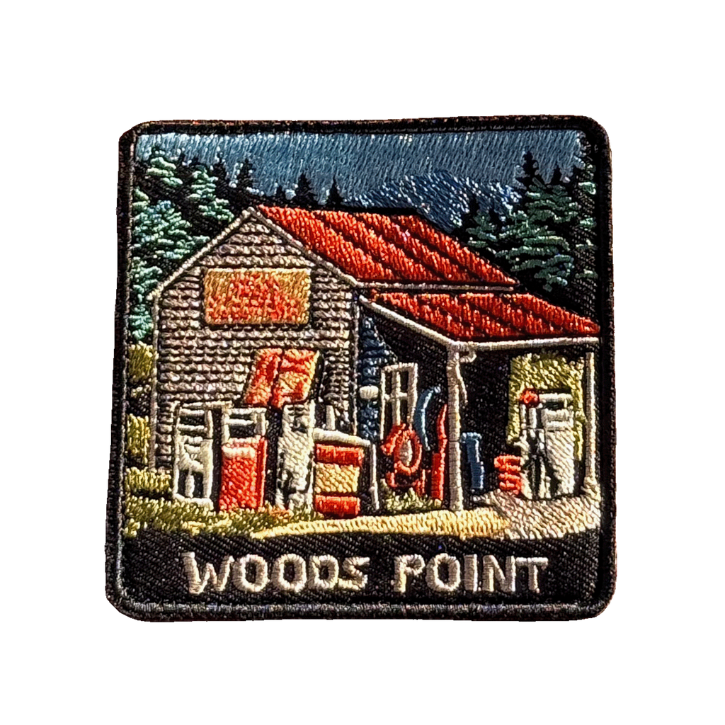Woods Point embroidered travel patch with a rustic high-country petrol station with old fuel pumps among pine trees; photographed on a transparent background.